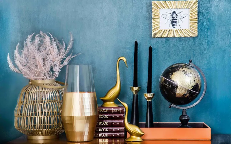 Modern shelf styling featuring gold and black accents, books, and decorative items.