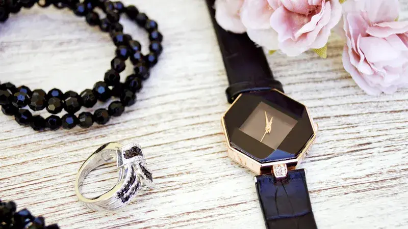 Image of a watch, ring, bracelet on a white stressed table introducing the concept of jewelry-specific ecommerce return policies.