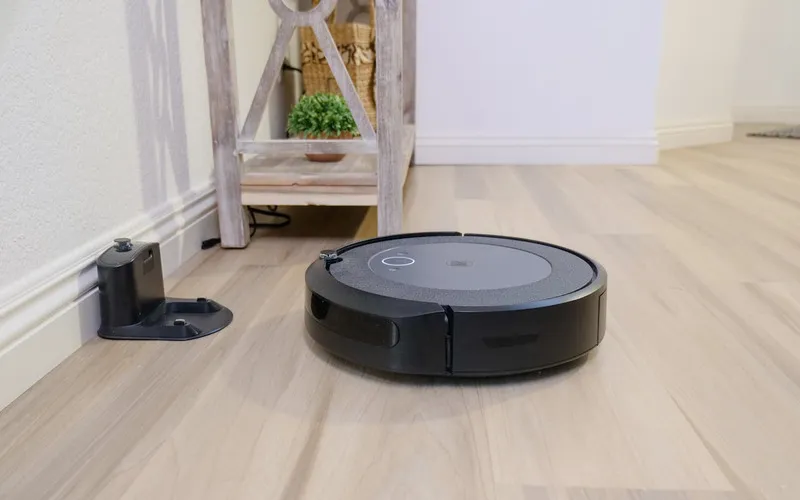 Smart vacuum cleaner docking at its base in a modern minimalist home.”
               title=